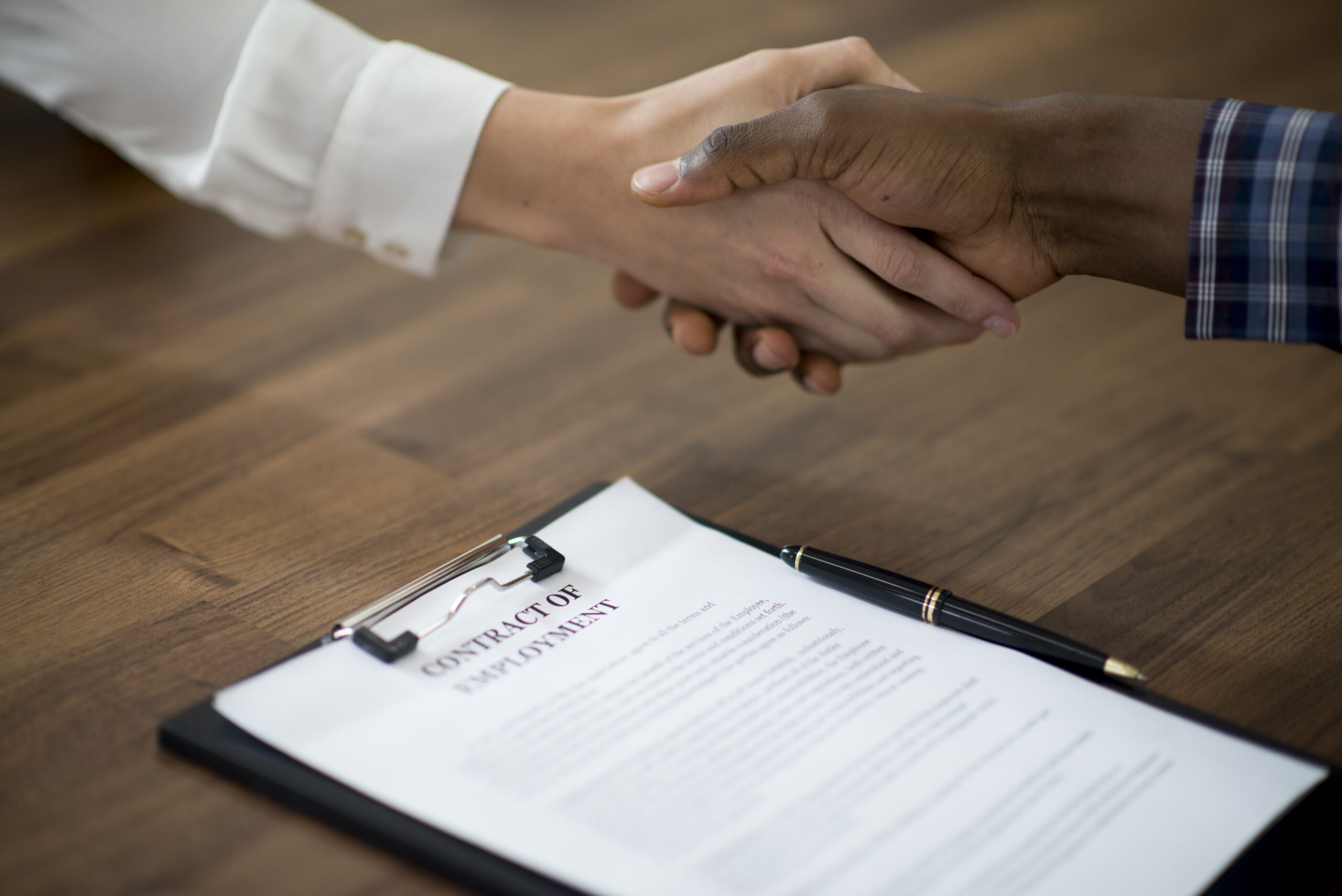 A woman is interviewing a new candidate for employment for her stsart up company. They are shaking hands.